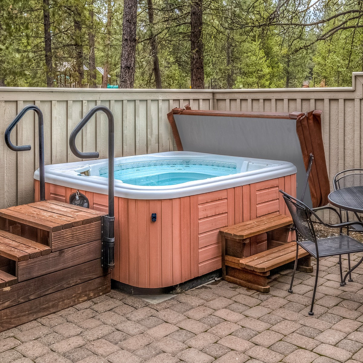 Brown 2.1m hot tub spa cover with a sleek design, surrounded by wooden steps and a stone patio, nestled in a forested area