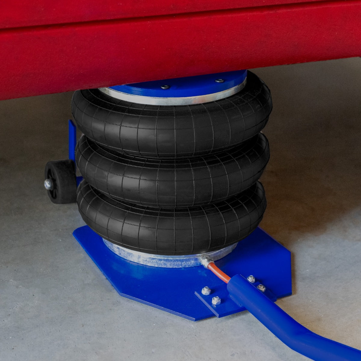 Black rubber air bags stacked on a blue metal base, supporting a vehicle, with a long lever handle for easy lifting and stability