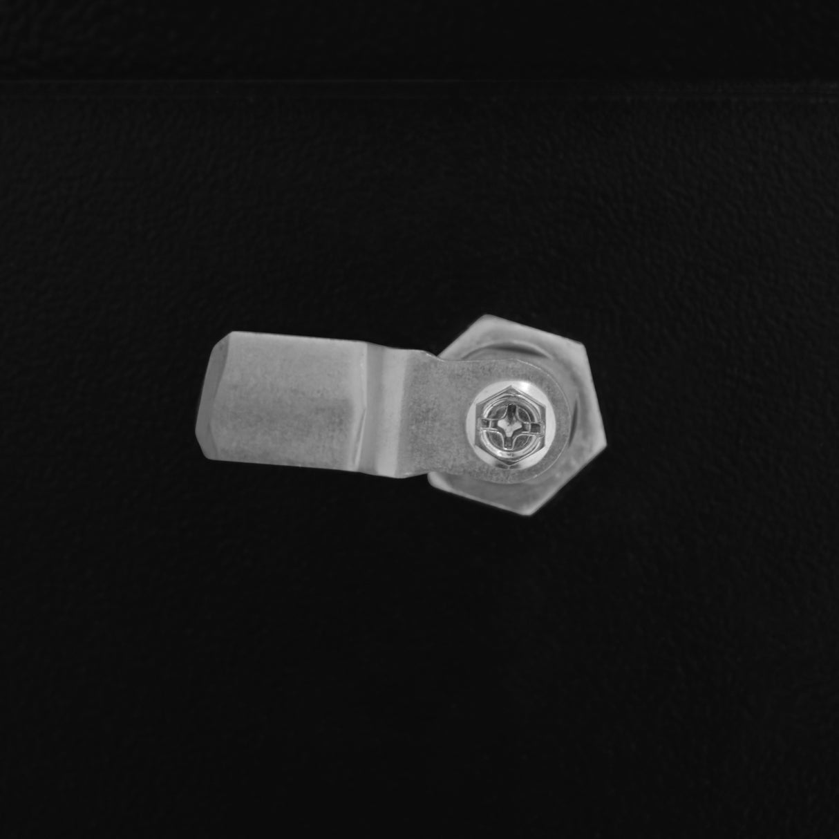 Close-up of a sturdy metal latch on a black gas bottle locker, featuring a hexagonal bolt and a textured surface for grip