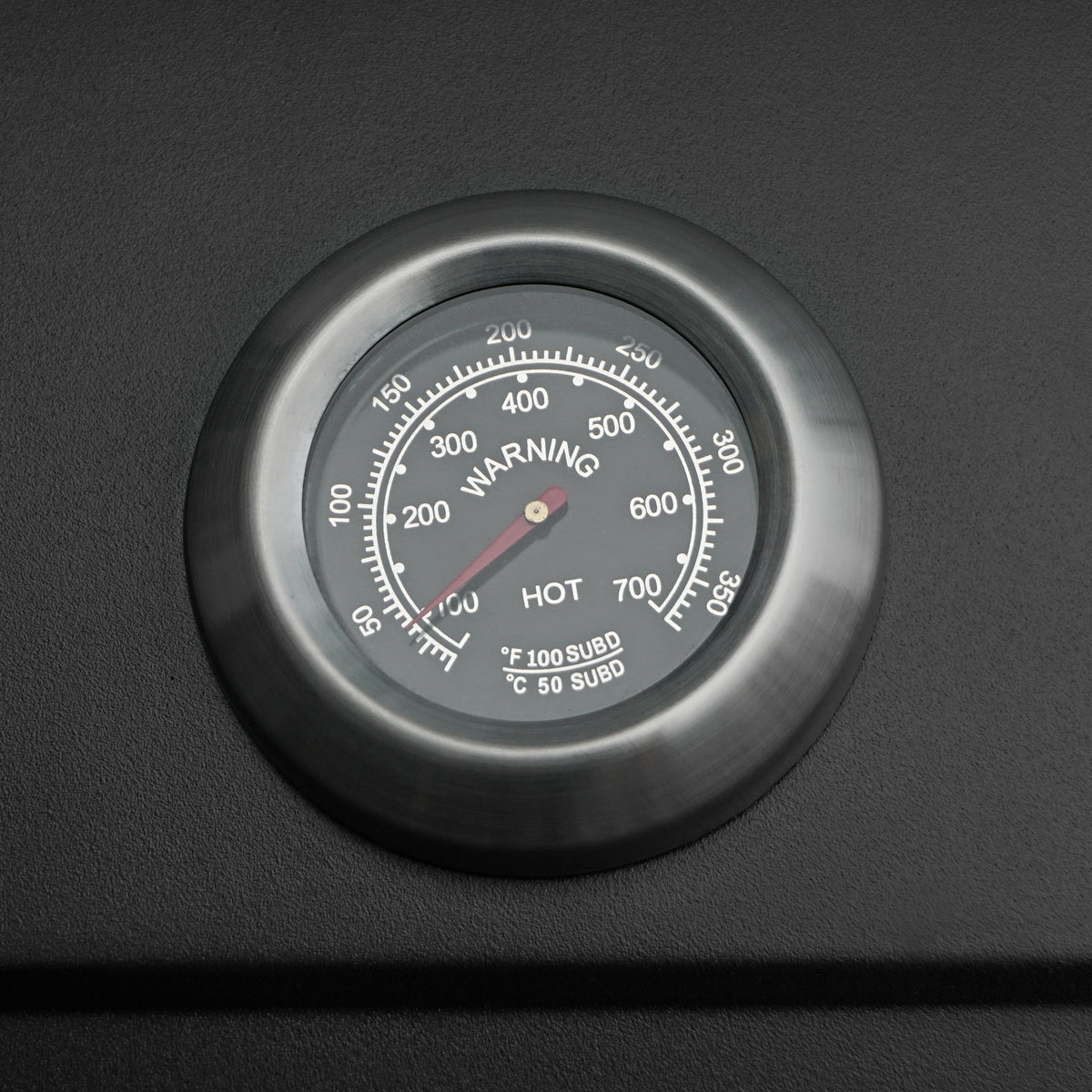 Close-up of a stainless steel BBQ smoker grill thermometer with a black dial, displaying temperature readings from 100°F to 600°F