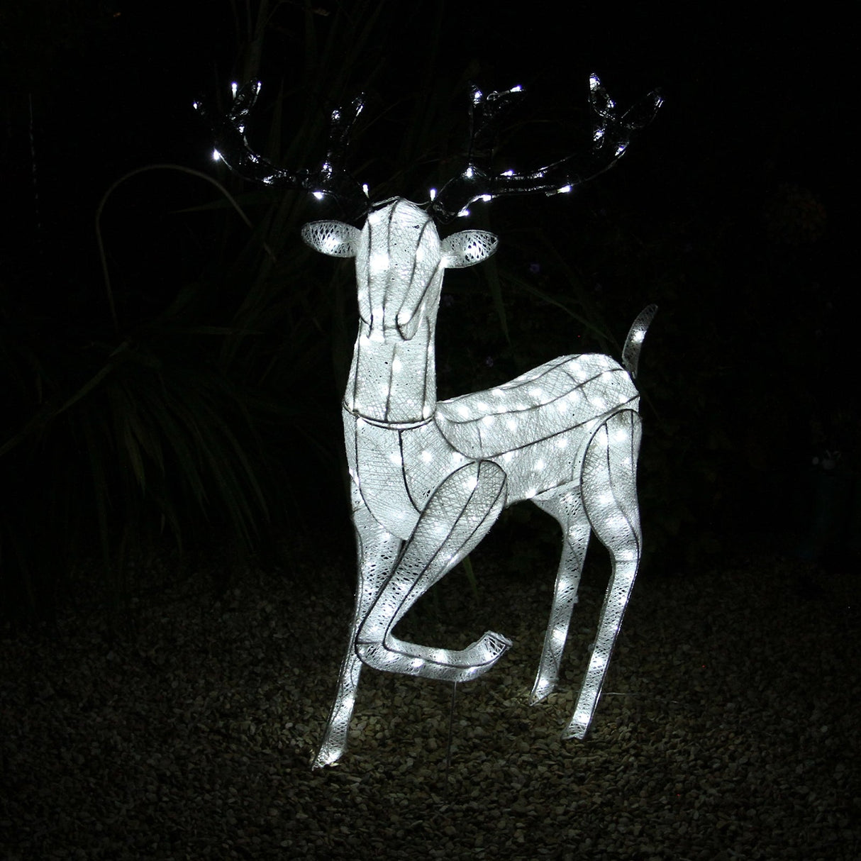 Large light-up stag reindeer with a sleek white frame, adorned with twinkling LED lights, standing gracefully on a gravel surface