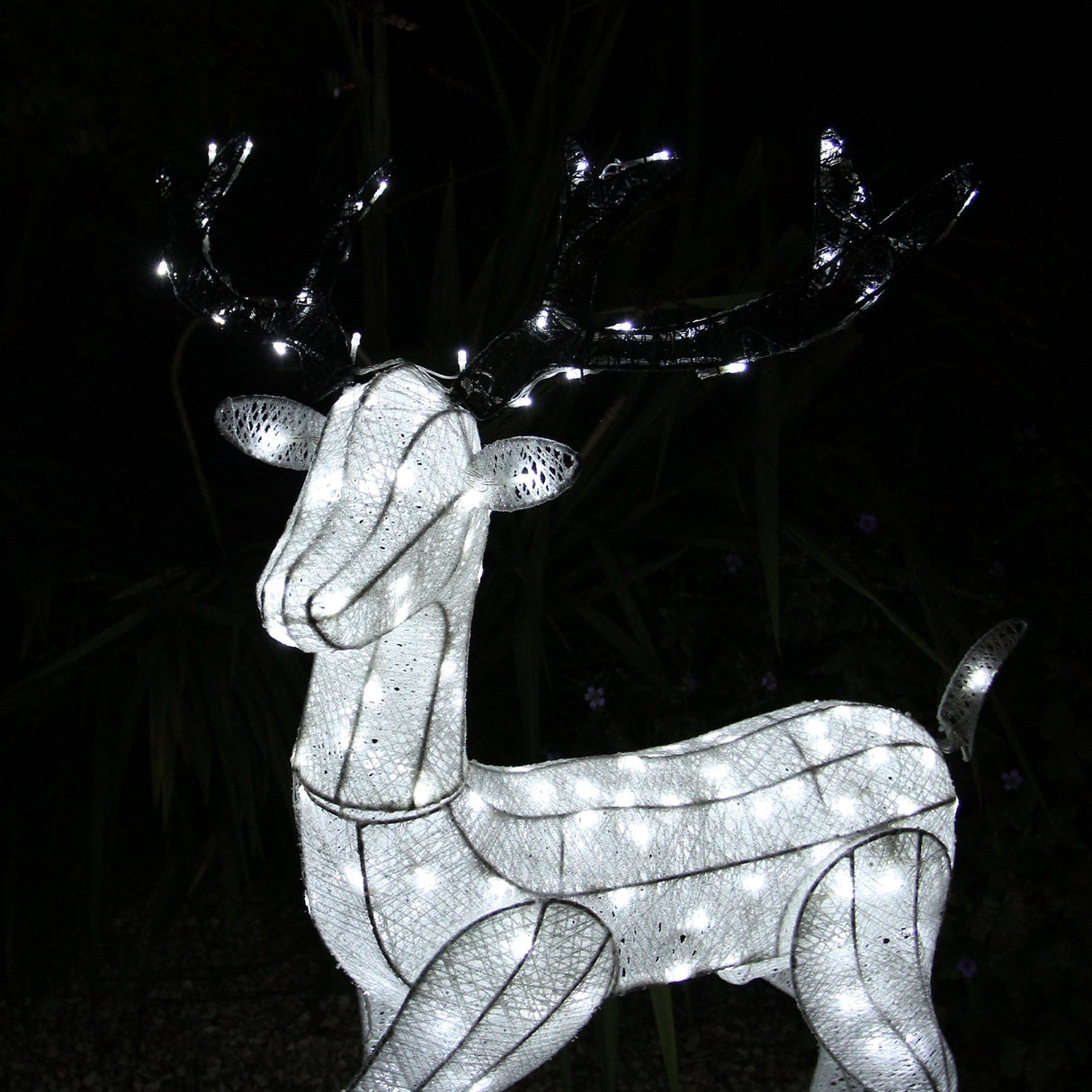 Large light-up stag reindeer with a shimmering white mesh body, illuminated by bright LED lights, set against a dark background