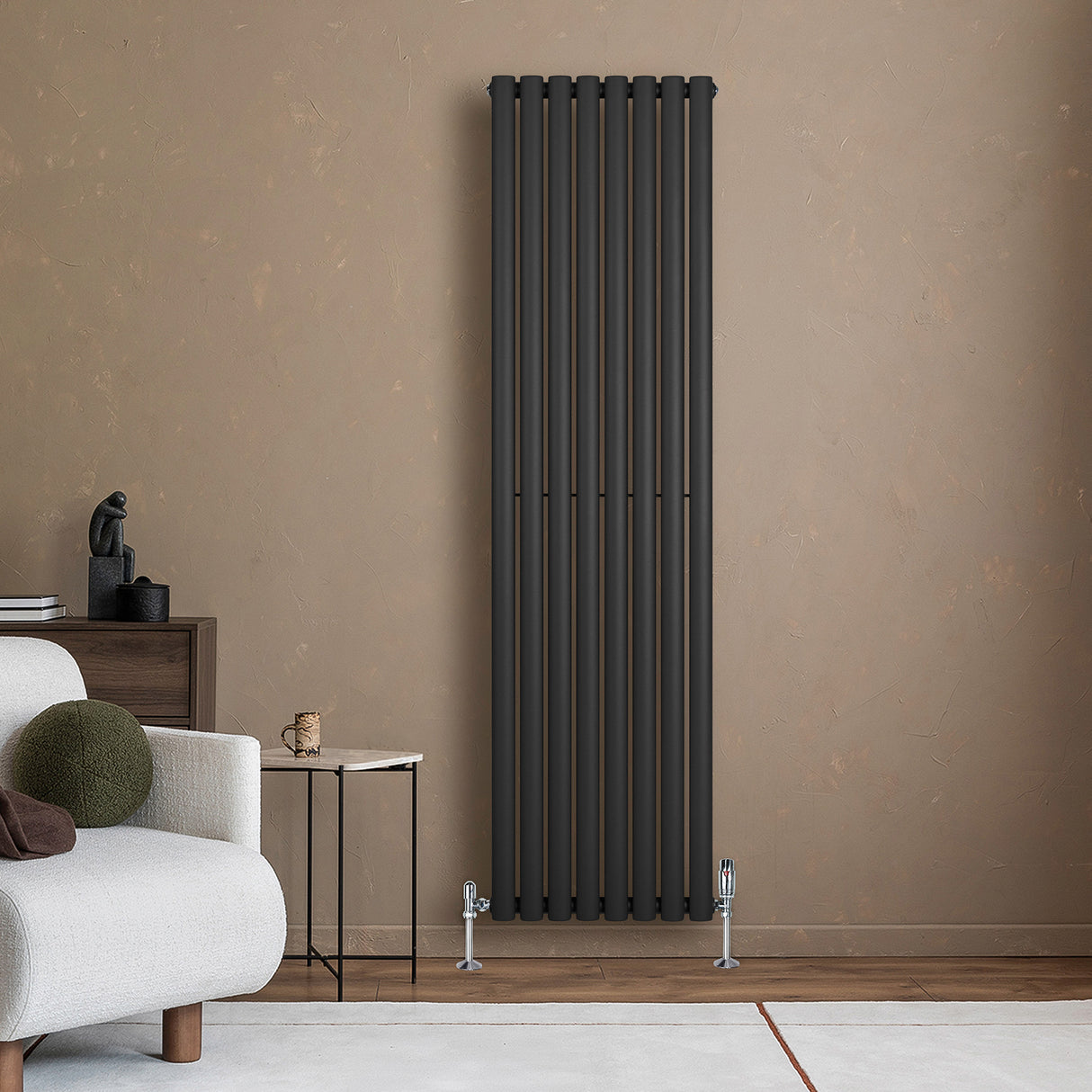 Sleek black oval single column radiator mounted on a textured wall, complemented by stylish valves and modern furniture nearby