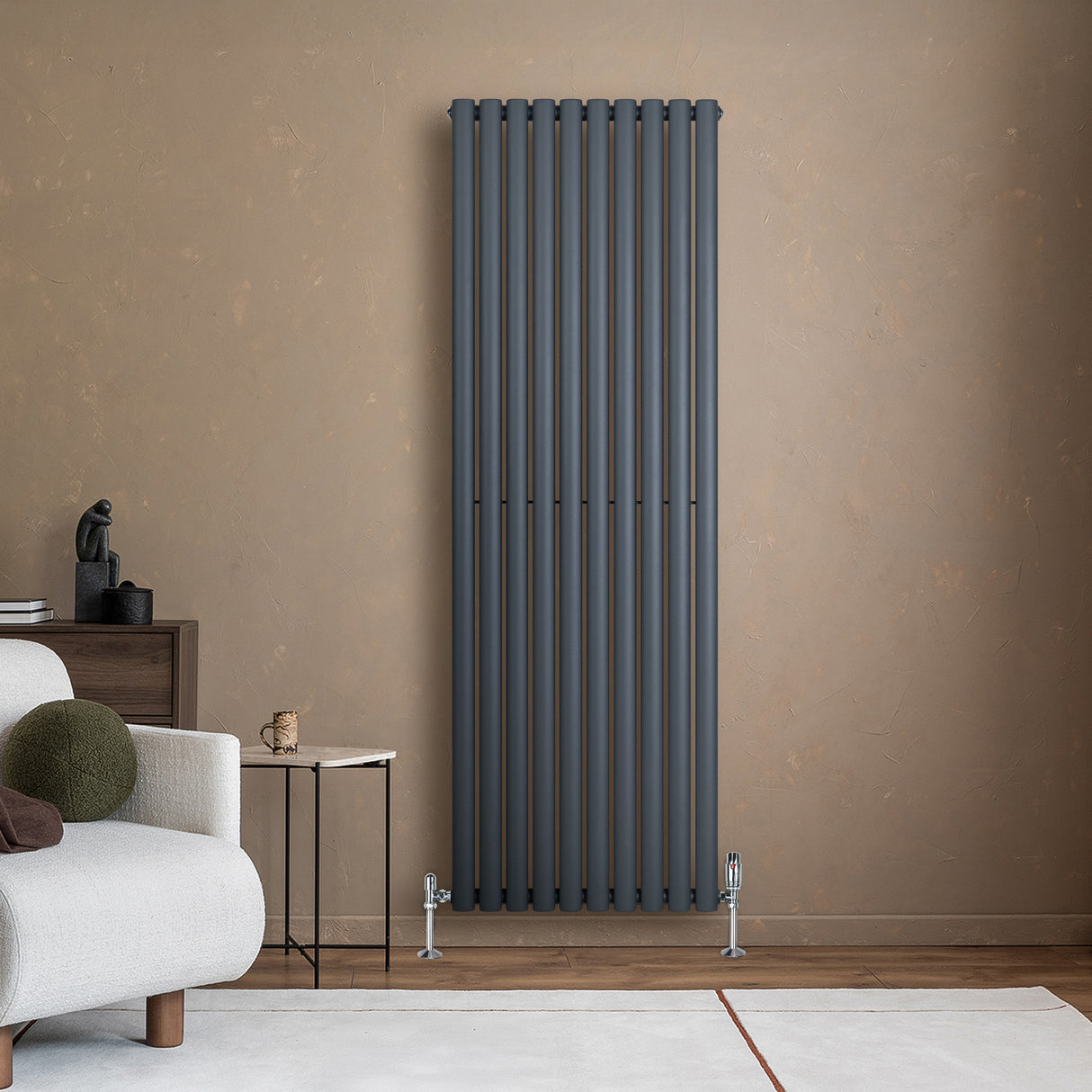 Sleek anthracite grey oval single column radiator mounted on a textured wall, complemented by stylish valves and modern decor