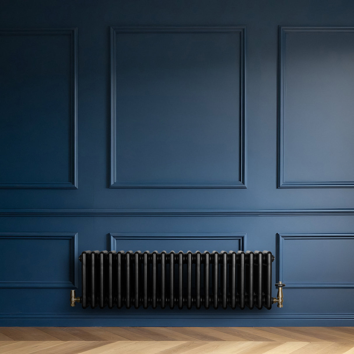 Traditional black 4 column radiator with brass valves, mounted against a deep blue wall, enhancing a classic interior design