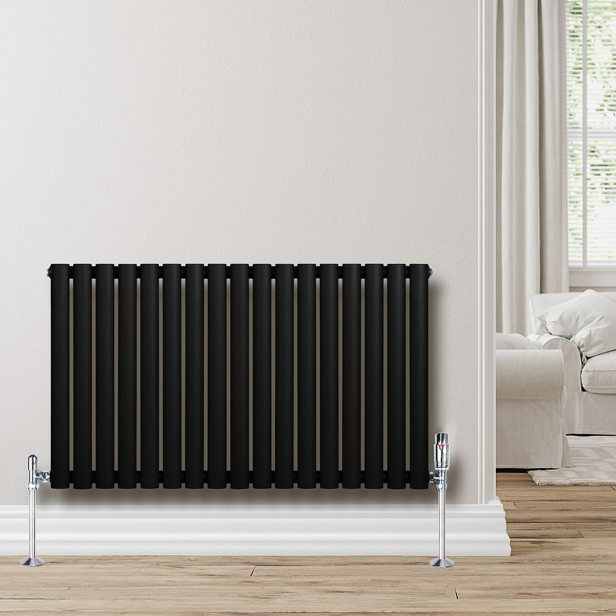Sleek black oval single column radiator, 600 x 1020mm, mounted on a light wall, complementing a cozy living room setting
