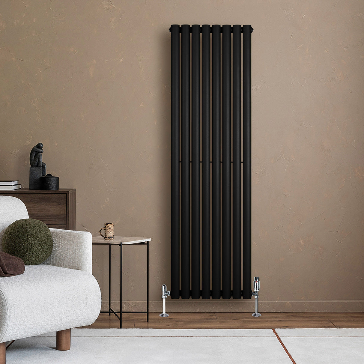 Sleek black oval single column radiator mounted on a textured beige wall, complementing a modern living room setting with a cozy sofa