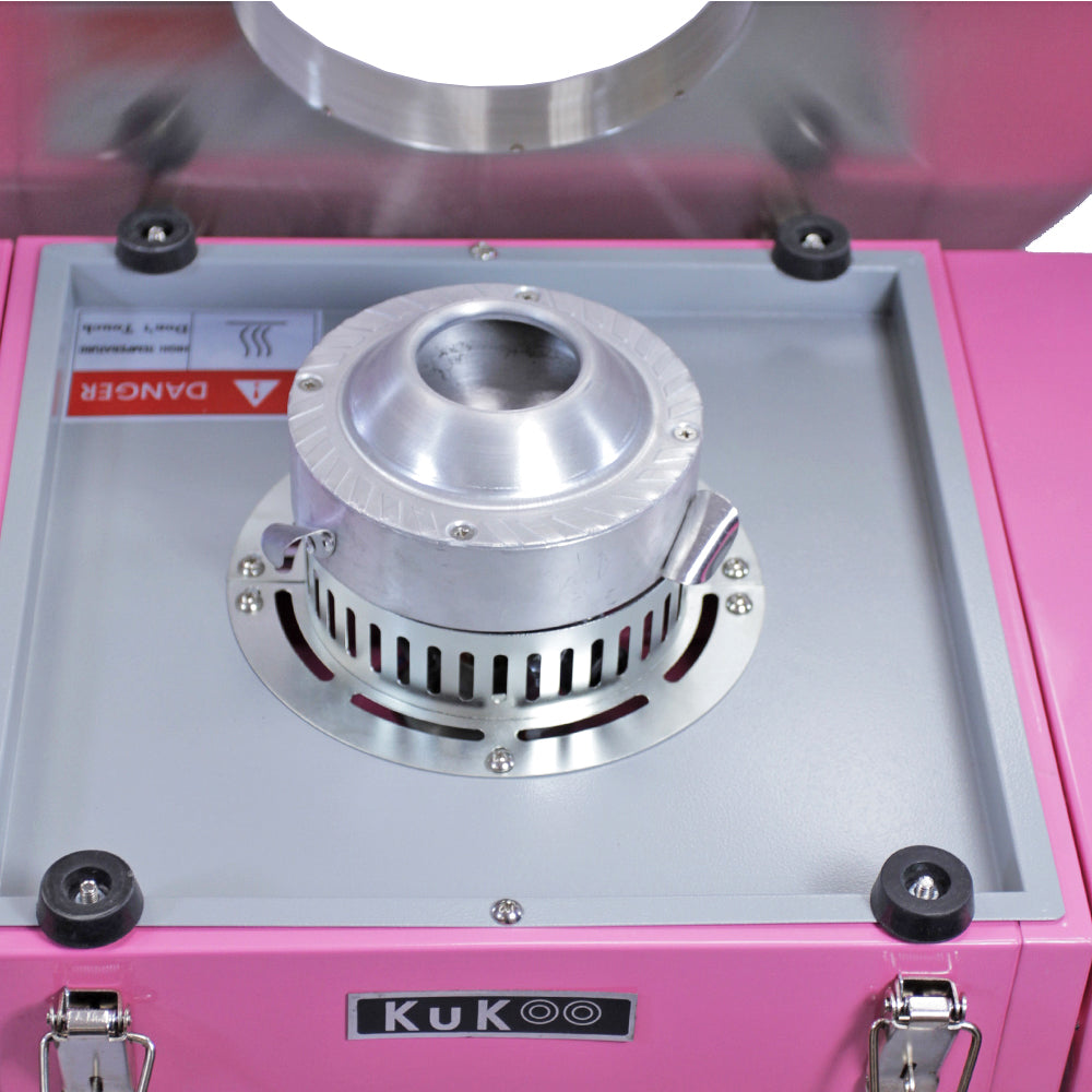 Pink candy floss machine with a shiny silver bowl, featuring a warning label and sturdy black rubber feet for stability