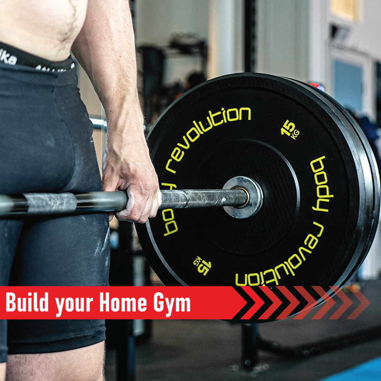 Close-up of a person lifting a Body Revolution Olympic barbell with black plates and vibrant yellow lettering in a gym setting