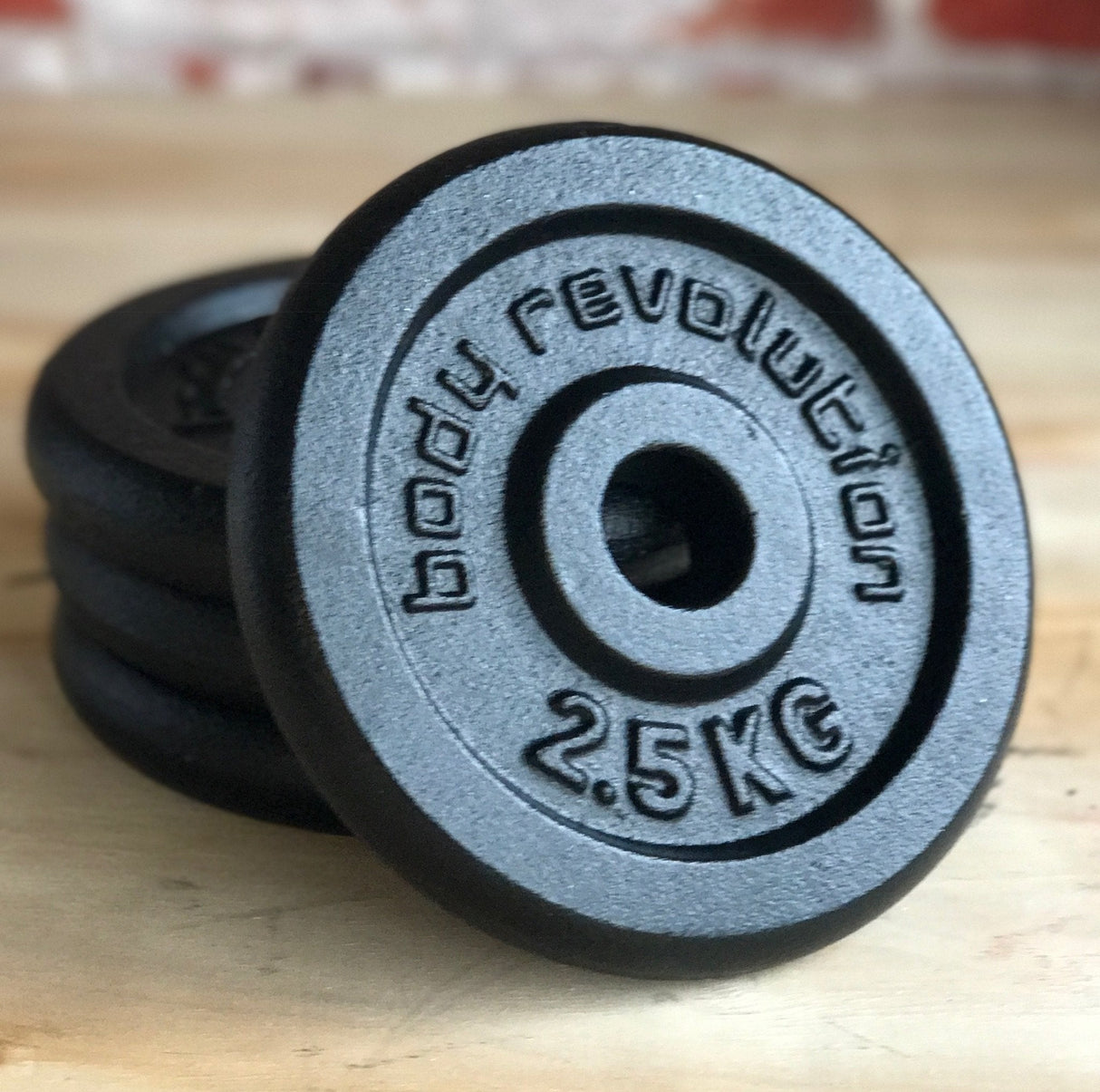 Cast iron weight plates with a textured black finish, featuring raised lettering and a central hole for easy handling, weighing 2.5 kg each