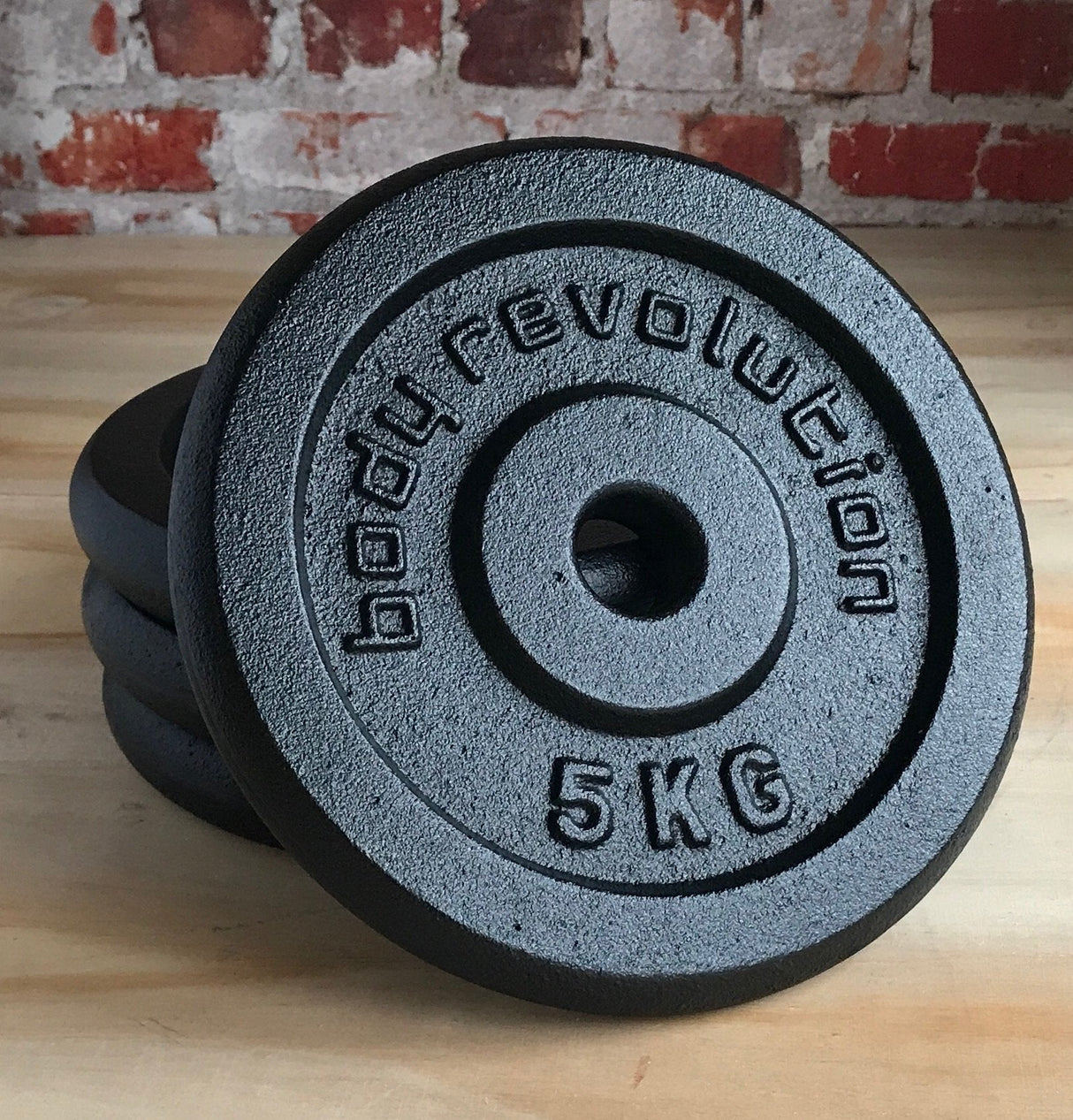 Heavy-duty cast iron weight plates with a textured black finish, featuring a central hole and embossed "5 KG" label for easy identification