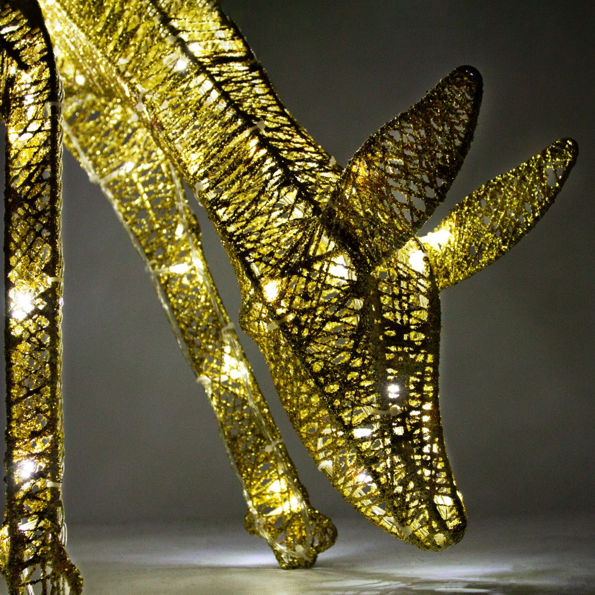 Glowing gold stag and doe set with intricate lattice design, illuminated by warm white lights, creating a festive ambiance