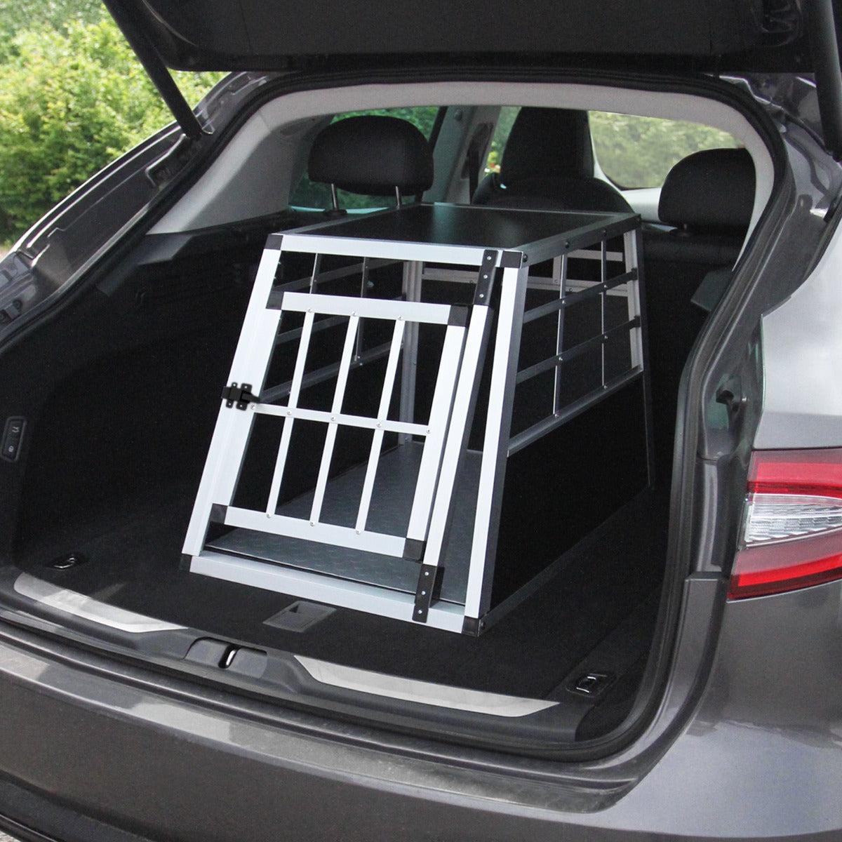 Small single door car dog crate in a sleek black and silver design, securely fitted in the trunk of a vehicle, featuring sturdy metal bars
