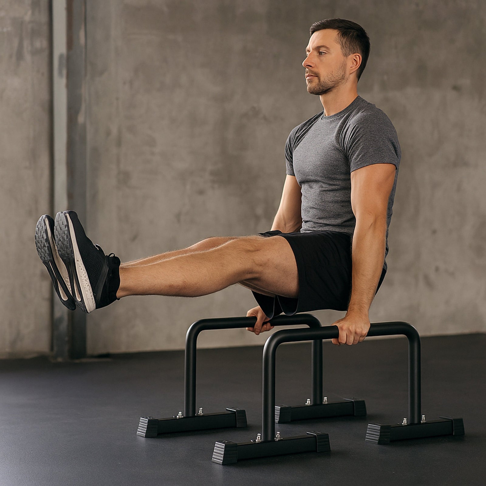 A man performs a leg raise on black parallel bars in a minimalist home gym, showcasing strength and focus in a modern space