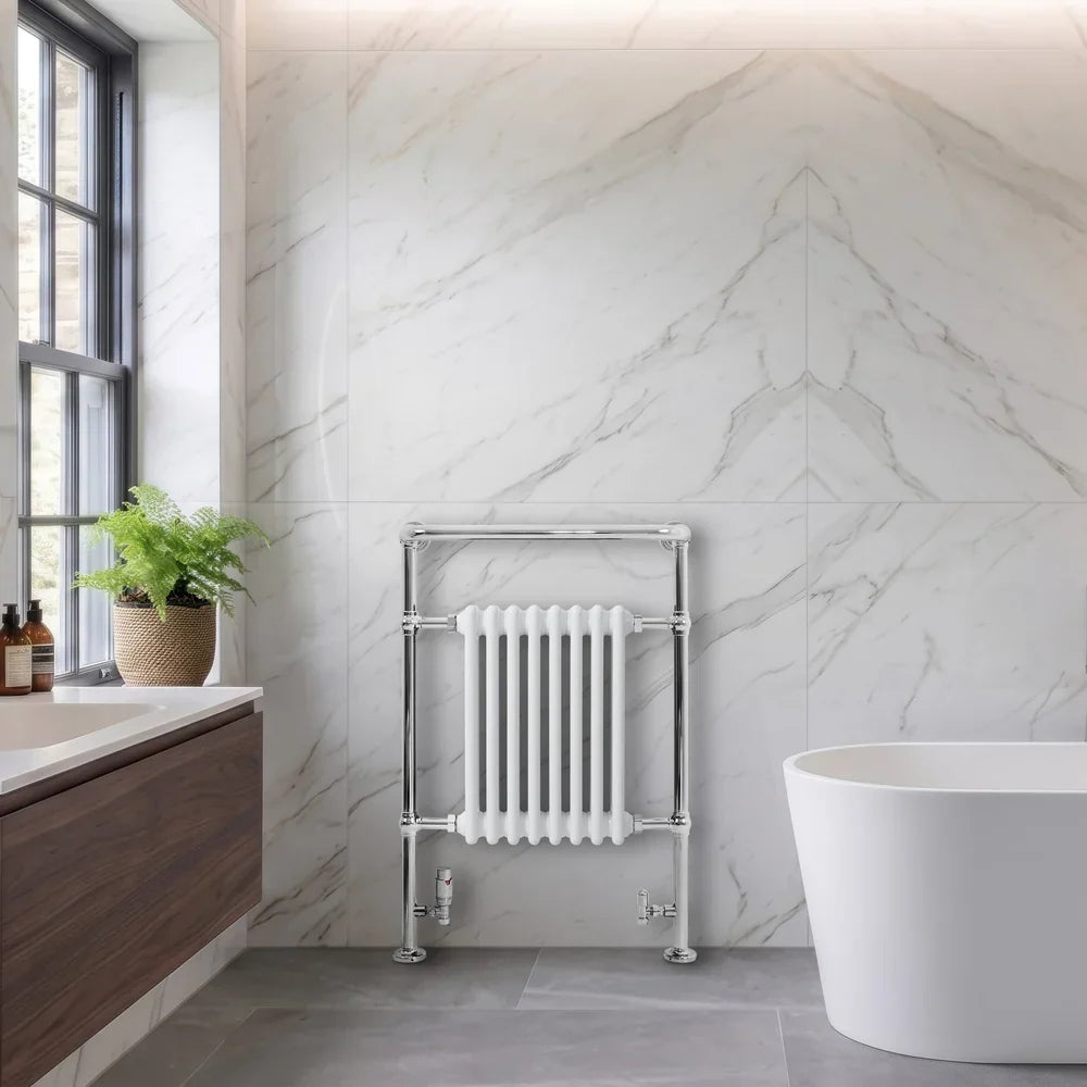 Traditional white heated towel rail radiator with chrome accents, mounted on a marble wall, beside a modern bathtub and sink