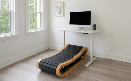 Curved treadmill with a sleek wooden frame and black textured running surface, positioned beside a modern standing desk and computer