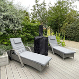 Black rain cover protecting a Kukoo outdoor pizza oven, surrounded by green foliage and two gray lounge chairs on a wooden deck