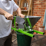 Sturdy green fruit crusher with a stainless steel hopper, being operated over a green bucket, ideal for juicing and cider making