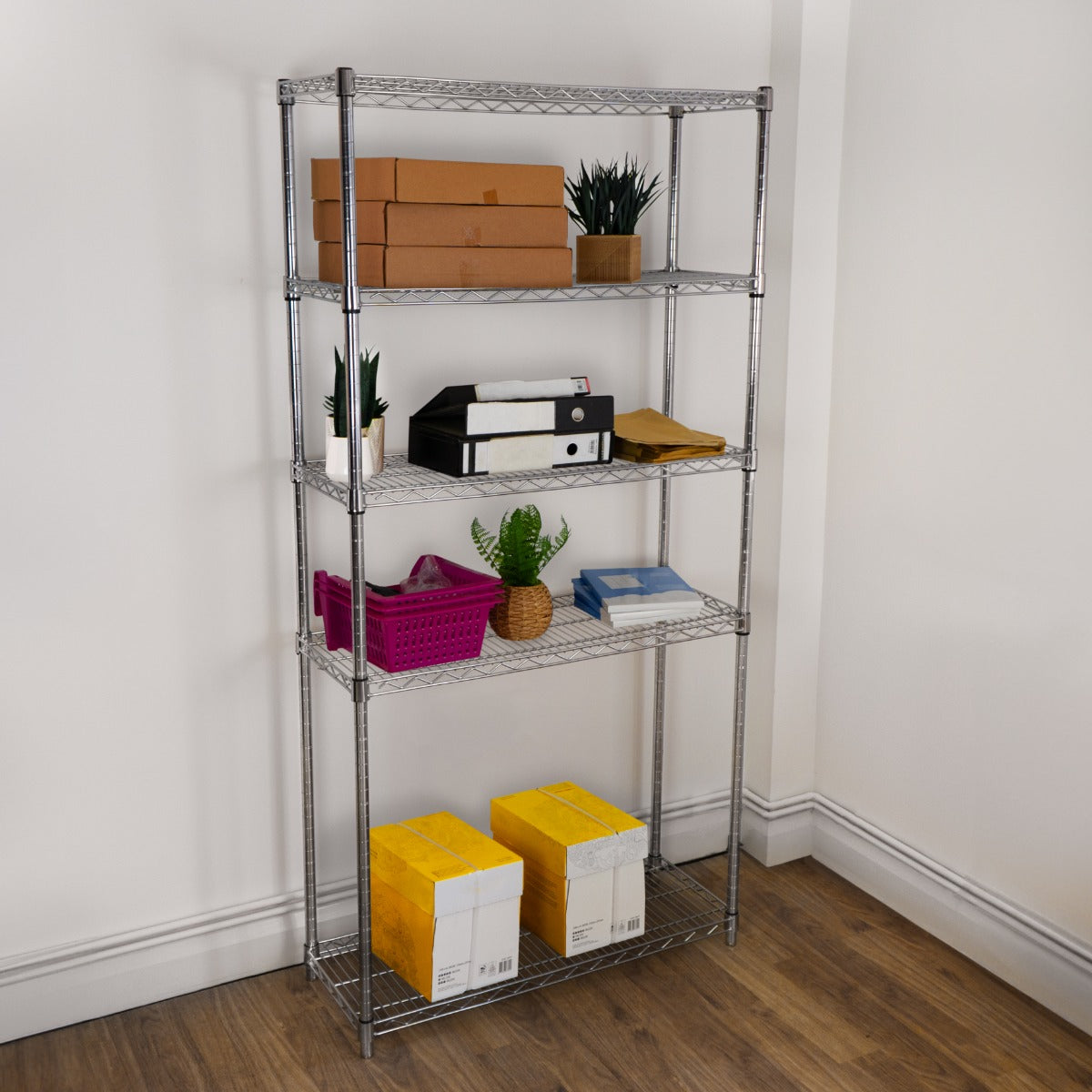 Metal wire racking unit with five shelves, featuring boxes, plants, and colorful storage bins, set against a light wall and wooden floor