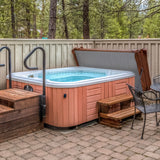 Brown 2.2m hot tub spa cover resting on a wooden deck, surrounded by trees and a stone patio, with steps leading up to it