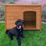 Medium wooden dog kennel with a slanted roof, featuring a cozy entrance, set on green grass with a black dog sitting nearby