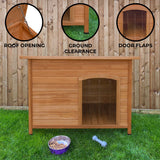Large wooden dog kennel with a slanted roof, ground clearance, and door flaps, set on green grass against a wooden fence