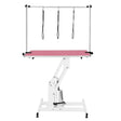 White hydraulic grooming table with a vibrant pink top, featuring adjustable height and three harness straps for secure pet grooming
