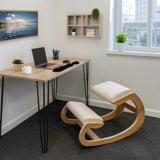 Ergonomic kneeling chair with a curved wooden frame and soft beige cushions, positioned in a modern office setting with a desk and laptop