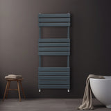 Sleek anthracite grey flat panel towel radiator, featuring horizontal slats, mounted on a dark wall beside a modern bathtub and stool