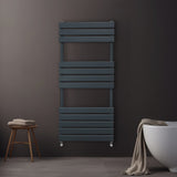 Sleek anthracite grey flat panel towel radiator mounted on a dark wall, featuring horizontal slats and a modern design, with a towel draped nearby
