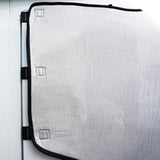 White motorhome screen cover with a textured surface, secured by black straps, designed for insulation and privacy