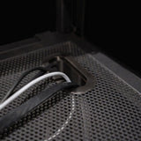 Metal cable management grommet on a textured black DJ booth surface, featuring multiple cables in white and black colors