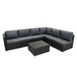 Modular 7-piece rattan furniture set in black with plush gray cushions, featuring a sleek coffee table and contemporary design