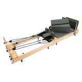 Wooden Pilates reformer with gray padded cushions, adjustable springs, and a sleek, modern design for effective workouts
