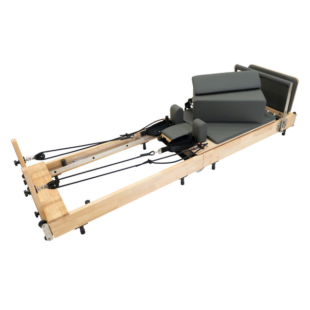 Wooden Pilates reformer with gray padded cushions, adjustable springs, and a sleek, modern design for effective workouts