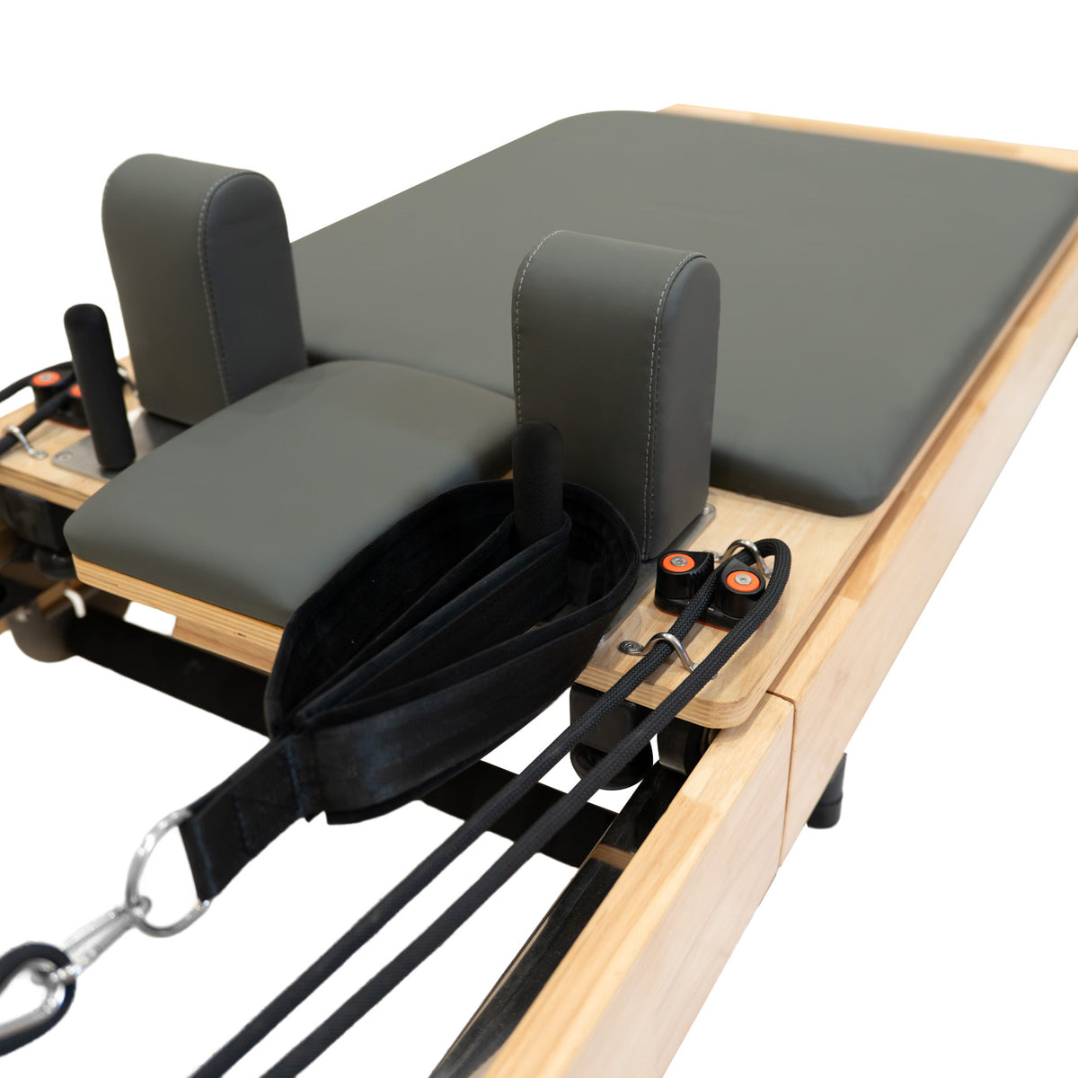 Reformer Pilates machine with a sleek wooden frame, gray padded surface, and adjustable straps for versatile workouts