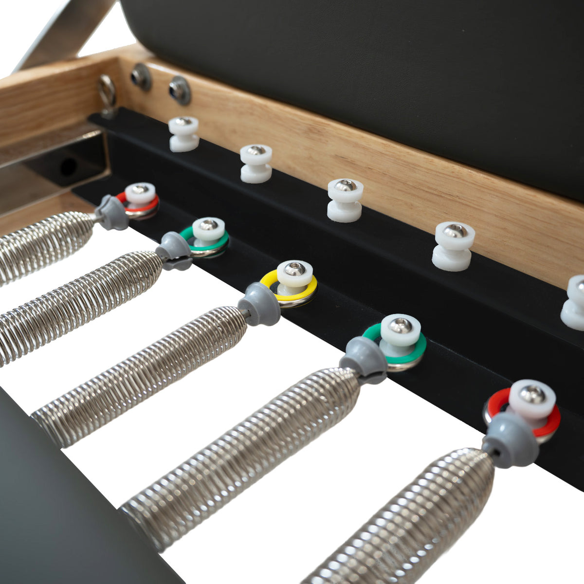 Close-up of a massage table's adjustable springs and colorful knobs, showcasing a sleek black surface and natural wood frame