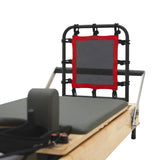 Reformer Pilates machine featuring a black frame, gray padded surface, and a red-trimmed mesh backrest for enhanced support