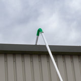 White gutter vacuum pole with a green curved attachment, positioned against a gray metal building under a cloudy sky