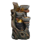 Rustic electric water feature with three stone bowls cascading water over a textured log design, illuminated by soft lighting
