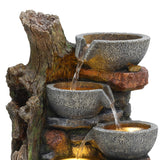 Rustic electric water feature with three textured stone bowls cascading water, surrounded by a natural wood-like base and earthy colors