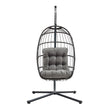 Black rattan hanging egg chair with a plush gray cushion, featuring a sturdy metal stand and a modern, stylish design