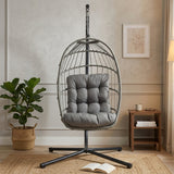 Stylish grey rattan hanging egg chair with plush cushions, suspended from a sturdy metal frame, set in a cozy living space