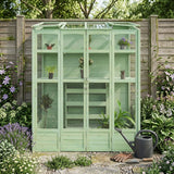 Victorian greenhouse in soft green, featuring glass panels, wooden shelves, surrounded by vibrant flowers and gardening tools