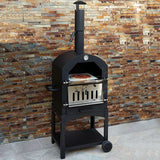 Black KuKoo outdoor pizza oven with stainless steel door, mounted on a sturdy cart, surrounded by a textured stone wall