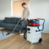 90L Maxblast industrial vacuum in white and red, being used on hardwood floor, featuring a flexible hose and metal nozzle, ideal for wet and dry cleaning