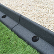 Flexible grey lawn edging with a smooth texture, separating gravel and lush green grass, ideal for garden landscaping projects