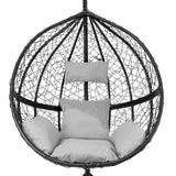 Black hanging rattan egg chair featuring a round woven design, plush white cushions, and a cozy, inviting shape for relaxation