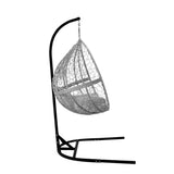 Stylish grey hanging rattan egg chair with a cozy cushion, suspended from a sleek black metal frame, perfect for outdoor relaxation