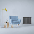 Anthracite grey flat panel radiator beside a light blue armchair, wooden side table, and modern floor lamp in a minimalist setting